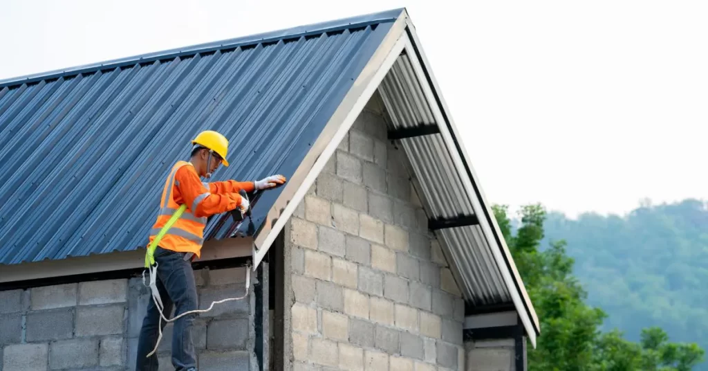 Construction worker installing corrugated metal roofing on shed structure - shed construction cost per square feet in India