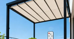 A modern retractable folding shed roof with a sleek black steel frame and light-colored waterproof fabric, installed over a terrace with minimalist outdoor lounge furniture and background greenery.